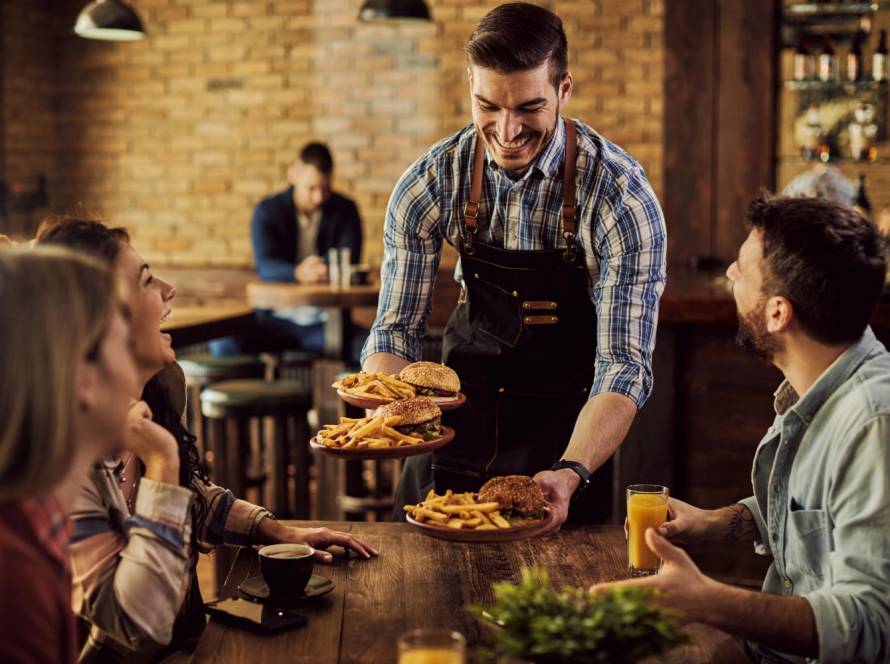 happy-waiter-serving-food-group-cheerful-friends-pub